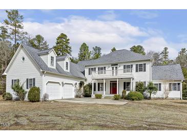 Stately two-story home featuring a red front door, second story balcony, and attached two-car garage at 419 Eagle Point Rd, Pittsboro, NC 27312