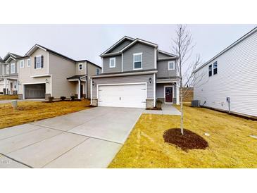 Charming two-story home with a spacious driveway and manicured front yard, showcasing modern architecture and curb appeal at 46 Coffee Tree Cir, Clayton, NC 27527