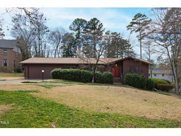 Charming home featuring a well-manicured lawn, mature trees, and a red front door, perfect for curb appeal at 817 Glen Eden Dr, Raleigh, NC 27612