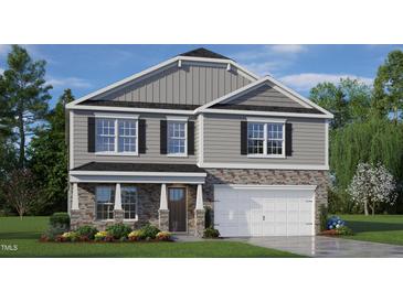 Charming two-story home features stone accents, gray siding, a two-car garage and a covered front porch at 112 Pisgah St, Sanford, NC 27330