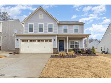 Charming two-story home with light blue siding, an attached garage, manicured lawn, and inviting curb appeal at 121 Mason Oaks Dr, Wake Forest, NC 27587