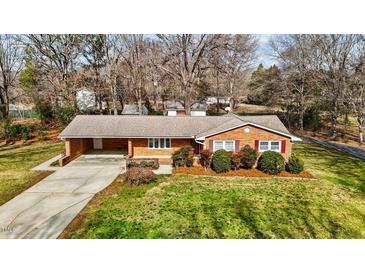 Charming brick home featuring a well-maintained lawn and mature landscaping, creating a welcoming curb appeal at 1837 Shamrock Dr, Burlington, NC 27215