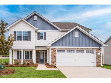 Charming two-story home with white siding, stone accents, and an attached two-car garage at 102 Wilderness Ct, Mebane, NC 27302