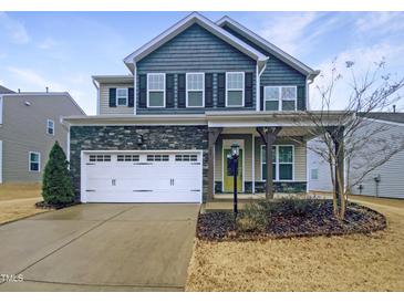 Charming two-story home with stone accents, a white garage door, and a well-maintained lawn at 157 W Copenhaver Dr, Clayton, NC 27527