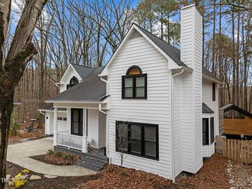 Stunning two-story home boasts a crisp white exterior, black trim, and a charming front porch at 202 Oxford Hills Dr, Chapel Hill, NC 27514
