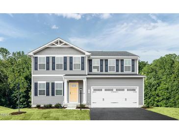 Charming two-story home featuring a two-car garage, yellow front door, and neatly manicured lawn with tasteful landscaping at 351 Tormore Dr, Sanford, NC 27330