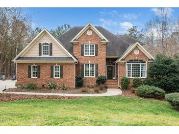 Charming brick home featuring a manicured lawn, mature trees, and a welcoming entrance at 7001 Millstone Ridge Ct, Raleigh, NC 27614