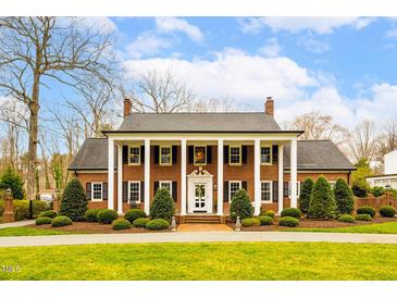 Stately brick home with white columns and manicured lawn under a blue sky at 712 Tarleton Ave, Burlington, NC 27215
