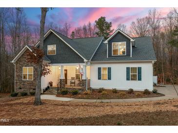 Charming two-story home featuring a stone facade, inviting front porch, and landscaped yard at 100 Lexington Ave, Zebulon, NC 27597