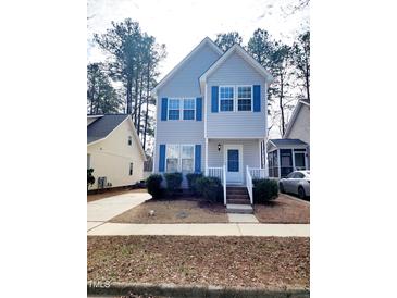 Charming two-story home with blue shutters and a well-maintained front yard with beautiful plants at 105 Cross Hill Ln, Holly Springs, NC 27540