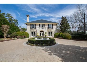 Stately two-story home with a circular driveway featuring a beautiful fountain and lush landscaping at 12132 Lockhart Ln, Raleigh, NC 27614