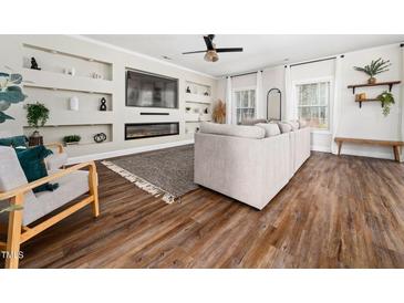Bright living room showcasing a large gray sofa, sleek fireplace, and custom built-in shelving at 325 Azalea Gaze Dr, Youngsville, NC 27596