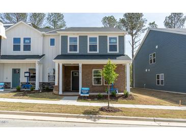 Charming two-story home featuring a brick facade, gray shingles, and a well-manicured lawn at 3719 Rosebush Dr, Zebulon, NC 27597