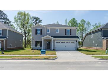 Charming two-story home with a two car garage and a well-manicured front yard at 3825 Rosebush Dr, Zebulon, NC 27597