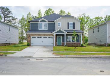 Beautiful two-story home featuring a two-car garage and covered front porch, surrounded by a lush green lawn at 3829 Rosebush Dr, Zebulon, NC 27597