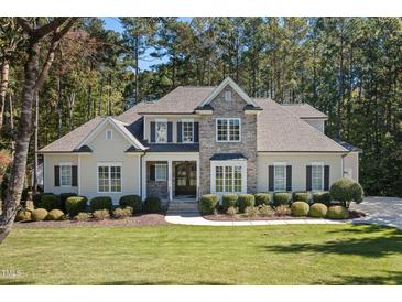 Elegant home with a stone facade, manicured lawn, and lush landscaping at 7004 Bartons Bend Way, Raleigh, NC 27614