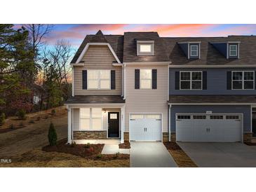 Charming townhome exterior with stone accents, a private garage, and a well-manicured lawn at 801 Pryor St # 48, Mebane, NC 27302