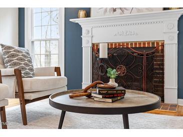 Living room features a fireplace with decorative mantle and round coffee table with decor at 112 Parkmeadow Dr, Cary, NC 27519