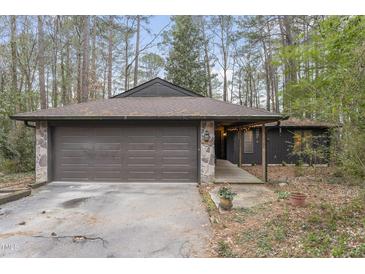Charming single-story home featuring a stone-accented facade, brown garage door and wooded surroundings at 118 Flora Mcdonald Ln, Cary, NC 27511