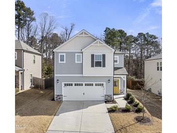 Charming two-story home boasts a yellow front door, attached garage, and landscaped front yard at 1401 Wrenn Rd, Durham, NC 27703