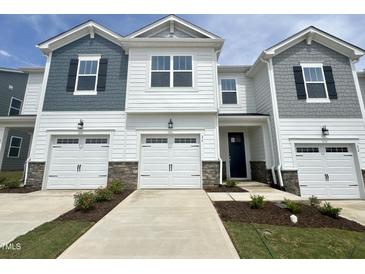 Beautiful townhome exterior showcases a two-car garage, lovely landscaping and grey and white color scheme at 26 Twin Birch Dr, Angier, NC 27501