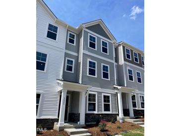 Charming townhome with gray and white siding, black door and window trim, and stone accents near the front entrance at 3009 Honeymyrtle Ln, Durham, NC 27703