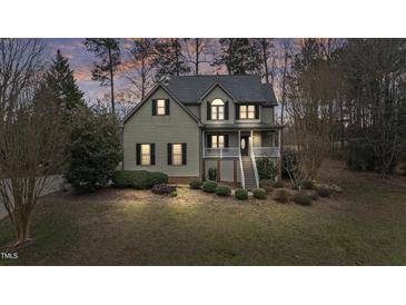 Charming two-story home with landscaped yard, inviting porch, and traditional architectural details, set amidst mature trees at 309 Neuse Ridge Dr, Clayton, NC 27527