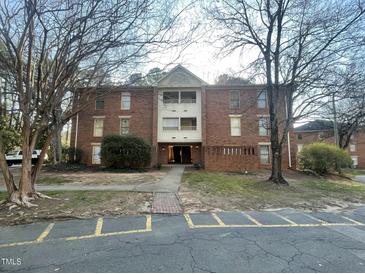 Three-story brick apartment building with mature trees and marked parking spaces at 3520 Ivy Commons Dr # 302, Raleigh, NC 27606