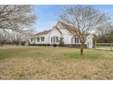 Charming white home with a beautiful yard, flowering trees, and a gated driveway at 582 Ebenezer Church Rd, Coats, NC 27521