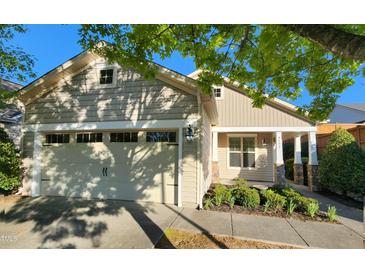 Charming home featuring a beige exterior, attached garage, and lovely front yard landscaping at 8504 Lasilla Way, Raleigh, NC 27616