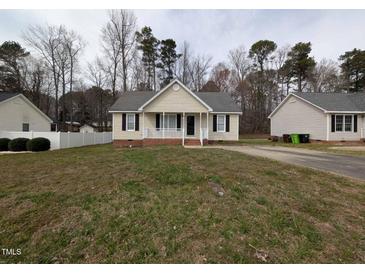 Charming single-story home with neutral siding, black shutters, and a cozy, white picket front porch at 1032 Holly Pointe Dr, Wendell, NC 27591