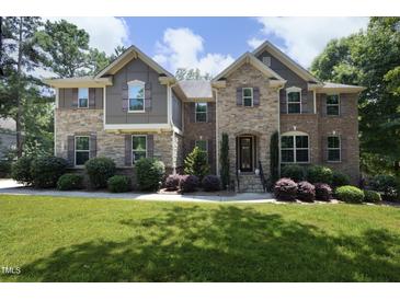 Beautiful two-story home featuring a well-manicured lawn and a stone and brick facade at 156 Stoney Creek Way, Chapel Hill, NC 27517