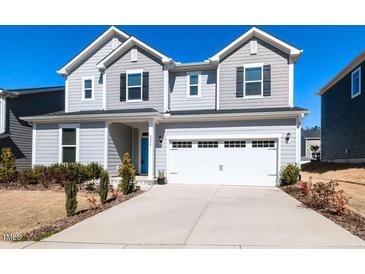 Charming two-story home with a blue front door and a spacious two-car garage and concrete driveway at 3354 Brunot St, New Hill, NC 27562
