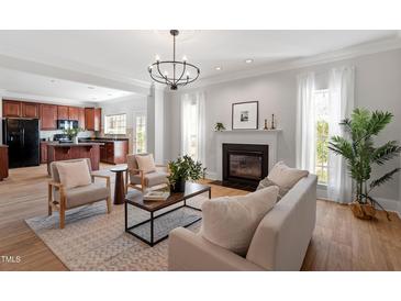 Bright living room with fireplace, hardwood floors, and open access to the kitchen at 3439 Archdale Dr, Raleigh, NC 27614