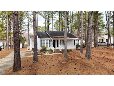 Charming one-story home nestled among trees with a welcoming front porch and landscaped garden at 432 Fowlkes St, Wendell, NC 27591