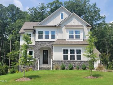 Beautiful two-story home featuring stone accents, white siding, and a well-manicured front lawn at 664 The Parks Dr, Pittsboro, NC 27312