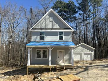 Two-story home with a front porch and a detached two-car garage, surrounded by trees at 1448B Maplewood Dr, Durham, NC 27704