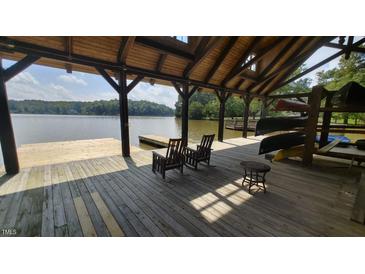 View of covered boat dock featuring lake access, rocking chairs, and canoe storage at 255 Hidden Lake Dr, Youngsville, NC 27596