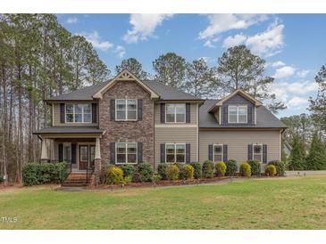 Charming two-story home featuring a blend of stone and siding, accented by well-manicured landscaping and a lush green lawn at 6712 Stepherly Way, Holly Springs, NC 27540