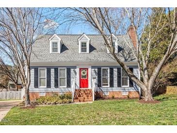Charming two-story home with a red front door and dormer windows, nestled in a well-manicured lawn and mature trees at 8617 Canoe Ct, Raleigh, NC 27615