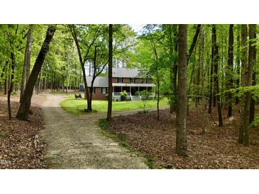 Charming brick home with a welcoming front porch surrounded by lush trees and a long, winding driveway at 1013 Traders Trl, Wake Forest, NC 27587