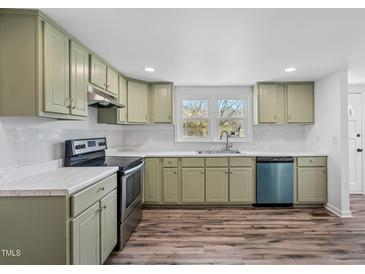 Charming kitchen featuring light green cabinets, stainless steel appliances, and wood-look floors at 608 N 15Th St, Erwin, NC 28339