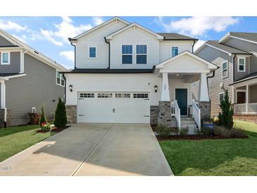 Charming two-story home with stone accents, a well-manicured lawn, and a two-car garage at 625 Sage Oak Ln, Holly Springs, NC 27540