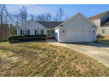 Charming single-story home featuring a manicured lawn, arched windows, and a two-car garage at 6624 Professor St, Raleigh, NC 27616