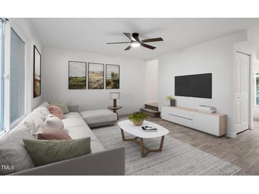 Bright living room featuring a modern sofa, neutral walls, and a ceiling fan at 1016 N Bend Dr, Raleigh, NC 27609