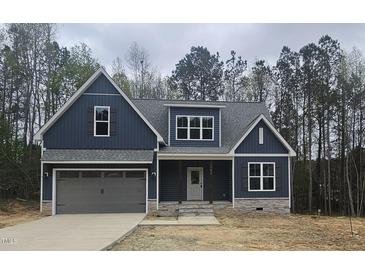 Charming home featuring a gray roof, blue siding, stone accents, and an attached two-car garage at 105 Leisure Ln, Louisburg, NC 27549