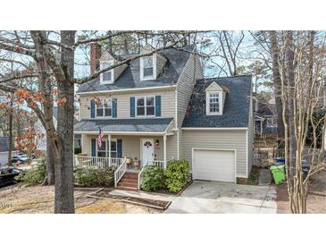 Charming two-story home featuring a front porch, attached garage, dormer windows, and traditional design elements at 1701 Point Owoods Ct, Raleigh, NC 27604