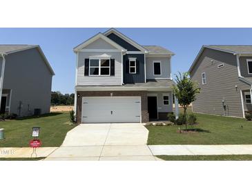 Charming two-story home with white garage, manicured lawn, and classic architectural details at 184 Bruce Dr, Dunn, NC 28334