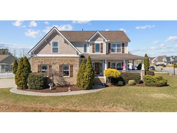 Charming two-story home featuring a brick facade, welcoming front porch, and manicured landscaping at 22 Old York Cir, Clayton, NC 27527