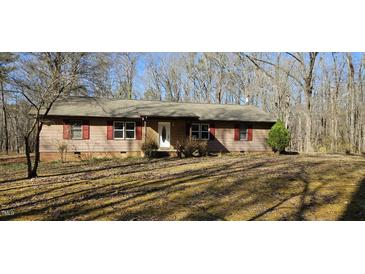 Charming single-story home with mature trees, red shutters, and covered entry on a sunny day at 319 Davis Rd, Hillsborough, NC 27278